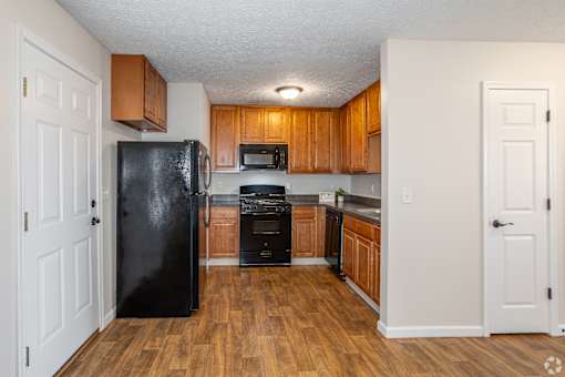 A kitchen with a black fridge and wooden cabinets.