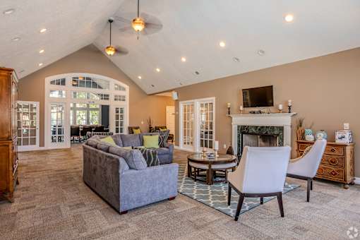 A living room with a grey couch, a white chair, a fireplace, and a television.