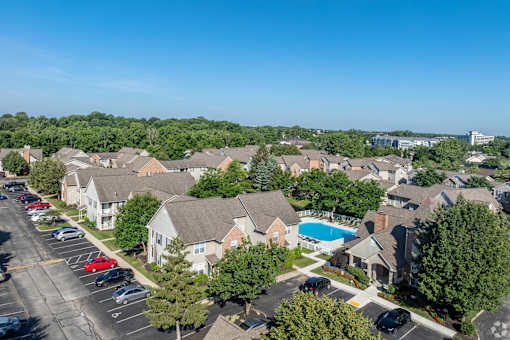 A bird's eye view of a residential area with houses, cars, and a pool.
