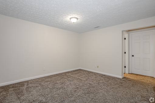 A room with a carpeted floor and a white door.
