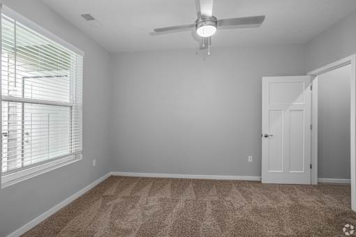 A room with a carpeted floor and a ceiling fan.