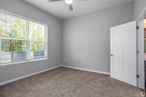 A room with a white door and a window with blinds.
