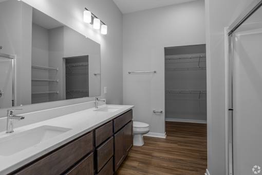 A bathroom with a sink, mirror, toilet and shower.
