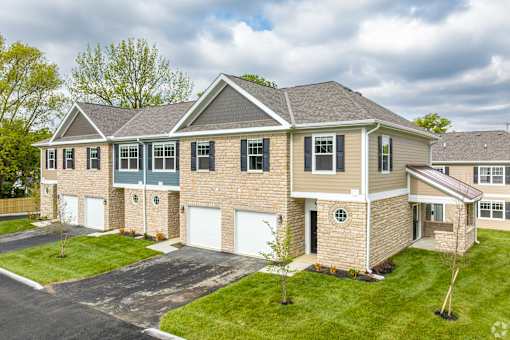 A large house with a grey roof and a driveway in front.