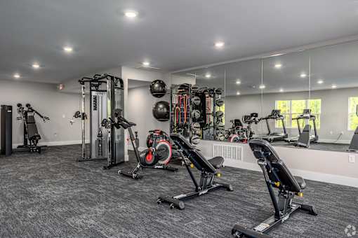 A spacious gym with a variety of equipment including treadmills, stationary bikes, and weight machines.