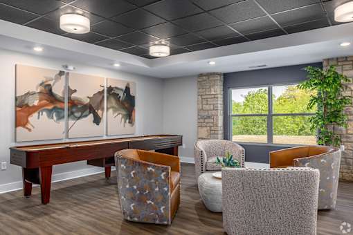 A room with a large painting on the wall and a wooden table with chairs around it.