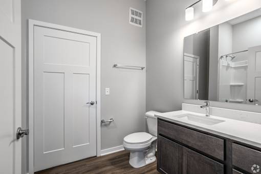 A white bathroom with a toilet, sink, and mirror.