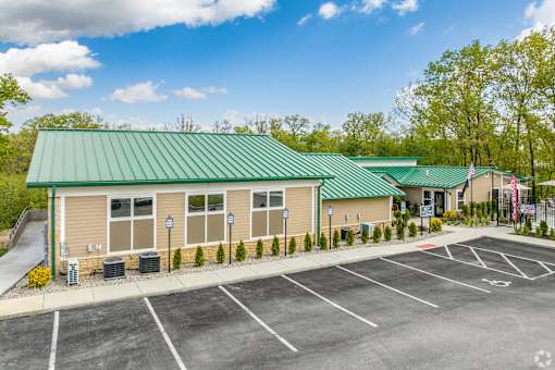 A building with a green roof and a parking lot in front.