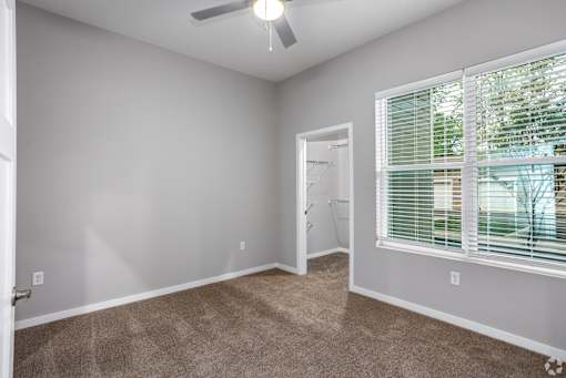 A room with a carpeted floor and a window with blinds.