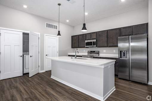 A modern kitchen with white countertops and stainless steel appliances.