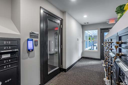 A hallway with a keypad door and a green plant on the wall.