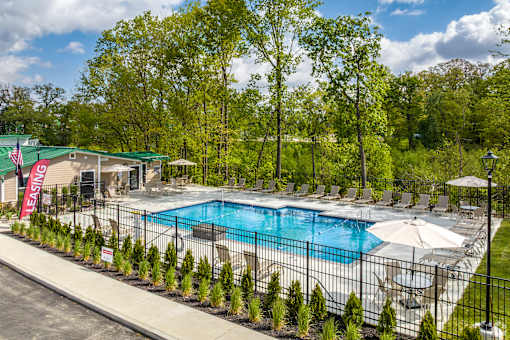A pool surrounded by trees and chairs.
