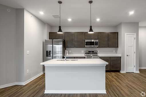 A modern kitchen with a white island and dark brown cabinets.