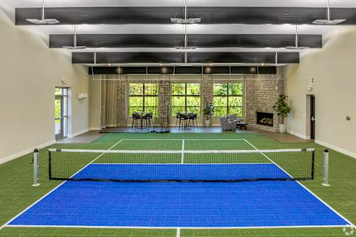 A tennis court is set up indoors with a net and two chairs.