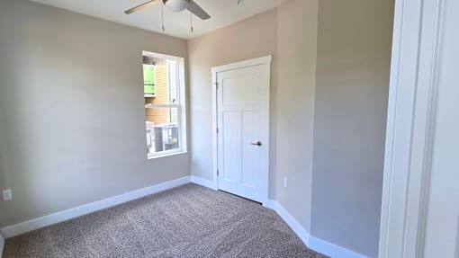 A carpeted bedroom with ceiling fan of an available apartment home at Greenwood Commons Apartments in Delaware, OH.
