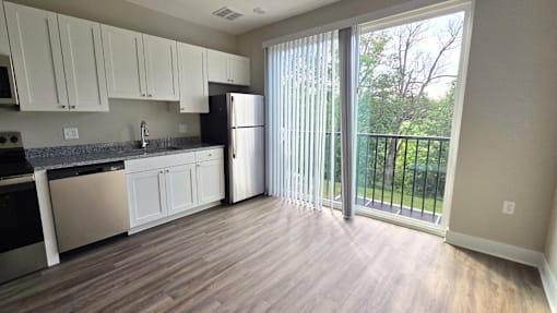 Kitchen and living area with balcony of an available apartment unit at Greenwood Commons Apartments in Delaware, OH.