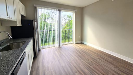 Kitchen and living area with balcony of an available apartment unit at Greenwood Commons Apartments in Delaware, OH.