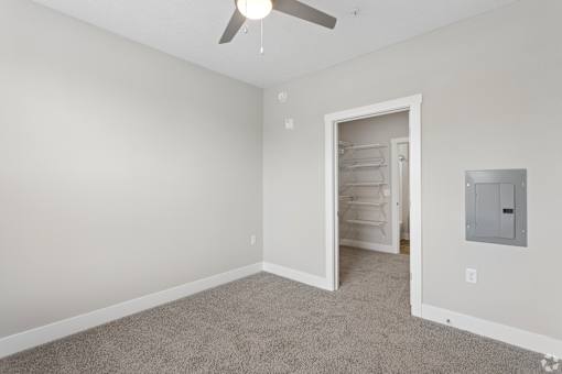 A room with a ceiling fan and a doorway leading to another room.