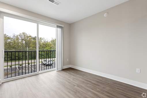 A room with a sliding glass door leading to a balcony.
