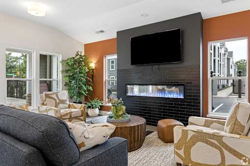 A living room with a grey couch, a black TV, and a fireplace.
