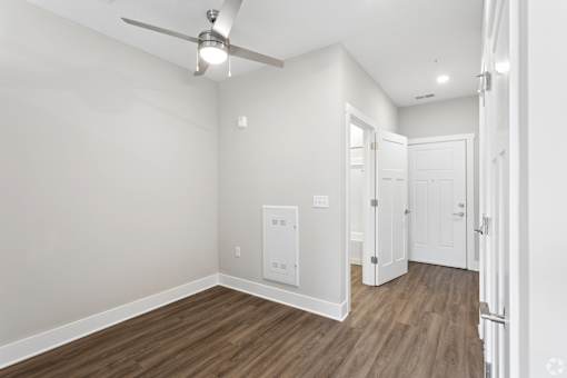 A room with a ceiling fan and wooden flooring.