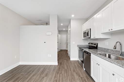 A kitchen with white cabinets and a wooden floor.