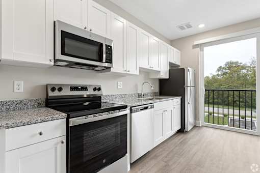 A kitchen with black appliances and white cabinets.