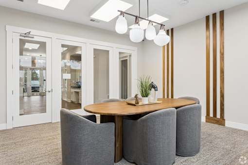 A modern dining room with a wooden table and grey chairs.