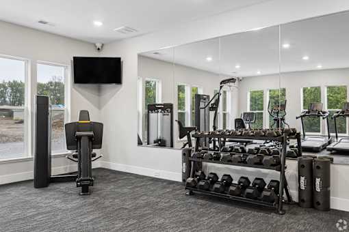 A home gym with a variety of equipment including a treadmill, weights, and a television.