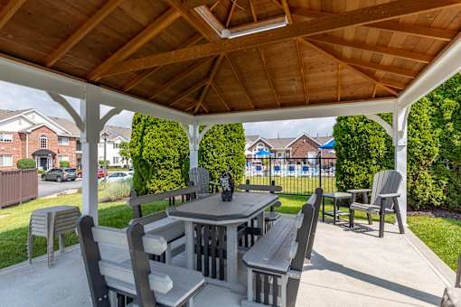 A wooden table and chairs are set up under a wooden roof.