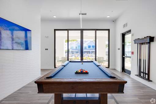 A pool table in a room with a view of the outside.at Imperial Crossing Luxury Apartment Homes, Bonita Springs, FL, 34134