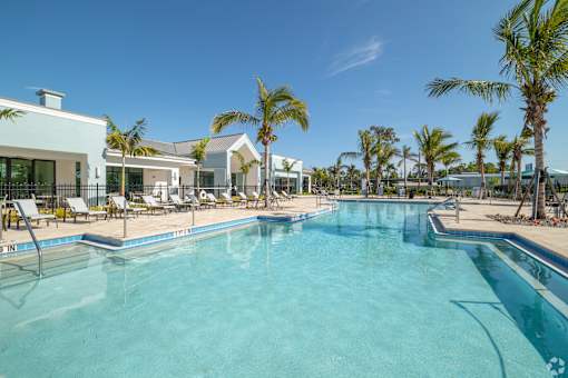 A swimming pool surrounded by palm trees and lounge chairs.at Imperial Crossing Luxury Apartment Homes, Bonita Springs, FL