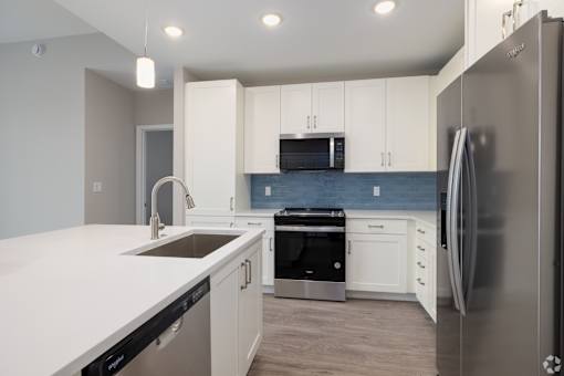 A modern kitchen with white cabinets and stainless steel appliances.at Imperial Crossing Luxury Apartment Homes, Bonita Springs, FL