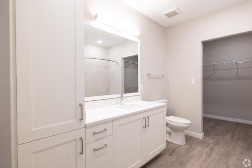 A white bathroom with a toilet, sink, and mirror.at Imperial Crossing Luxury Apartment Homes, Bonita Springs, FL, 34134