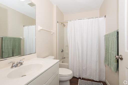 A white bathroom with a toilet, sink, and shower.