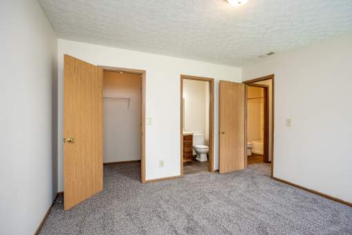 A room with carpeted floor and three open doors.