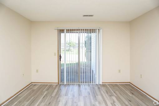 A room with a sliding glass door and wooden flooring.