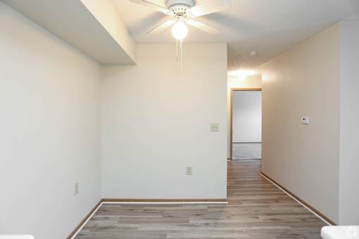 A room with a ceiling fan and wooden flooring.