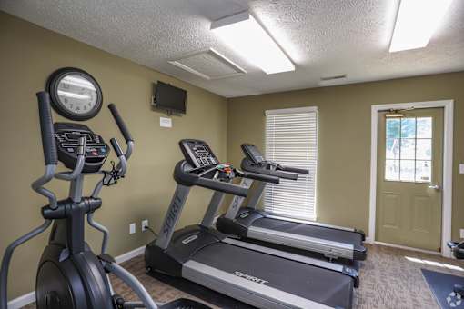 A home gym with a treadmill, elliptical trainer and a stationary bike.
