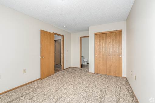 Carpeted bedroom, closet, and attached bathroom of a River Valley apartment home in Lancaster, OH.