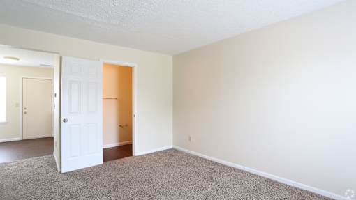 A room with a carpeted floor and two doors, one of which is open.