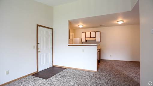 Main living area and kitchen of a River Valley apartment home in Lancaster, OH, with carpeting and cabinets.