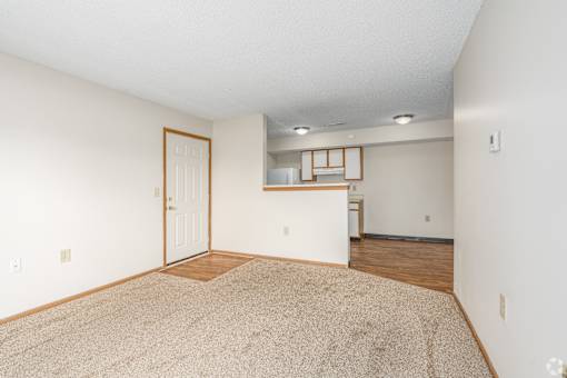 Main living area and kitchen of a River Valley apartment home in Lancaster, OH, with carpeting and cabinets.