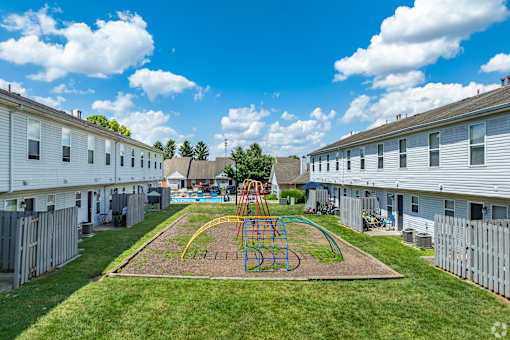 A playground with a swing set in the middle of a grassy area at River Valley Apartments in Lancaster, OH.