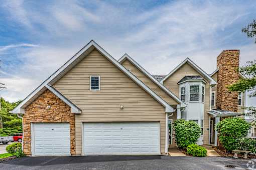 A two-car garage is attached to a house with a brick chimney.