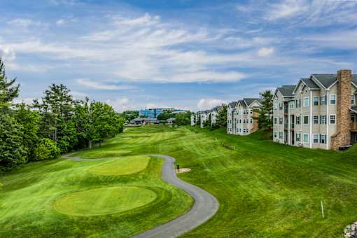 A golf course with a green and a building in the background.