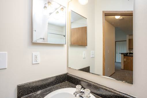 A bathroom with a sink, mirror, and light switch.