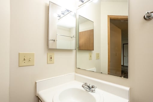 A white sink in a bathroom with a mirror above it.