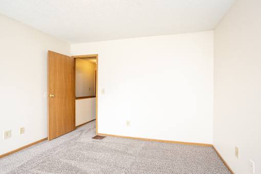 A room with a carpeted floor and a wooden door.