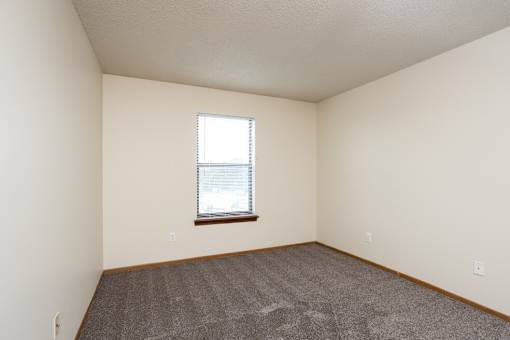 A room with a window and carpeted floor.